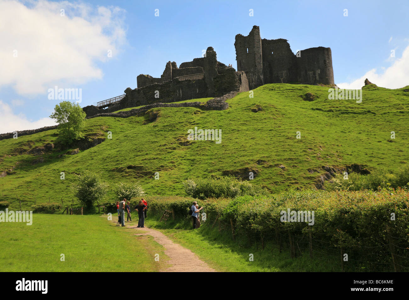 Les marcheurs en direction de Carreg Cennen Castle, l'un des châteaux les plus spectaculaires au Pays de Galles Banque D'Images