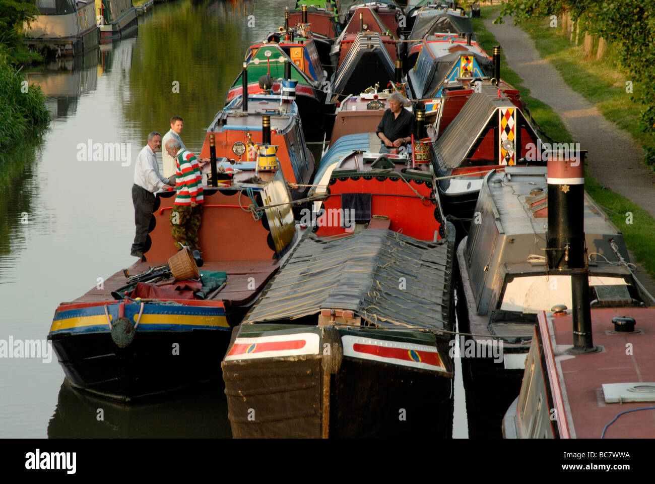 Quatre hommes debout et parler sur les ponts de travail traditionnels jusqu'à poitrine profonde narrowboats trois sur le canal à Braunston Banque D'Images