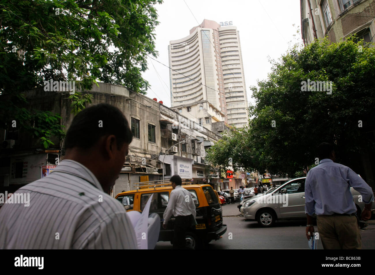 Les hommes d'affaires à pied sur la rue avec le Bombay Stock Exchange (BSE) visible à l'arrière-plan de Mumbai en Inde Banque D'Images