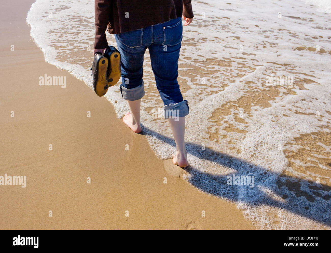 Une jeune femme prendre une promenade sur la plage Banque D'Images