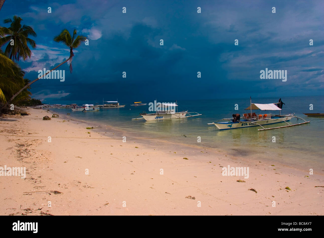 Bancas Local sur une plage de sable blanc bordée de palmiers, les nuages de tempête en arrière-plan. Banque D'Images