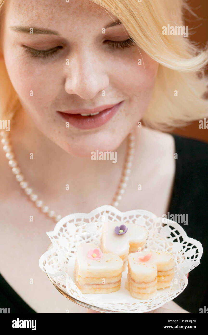 Woman holding dish contenant trois petit fours - Banque D'Images