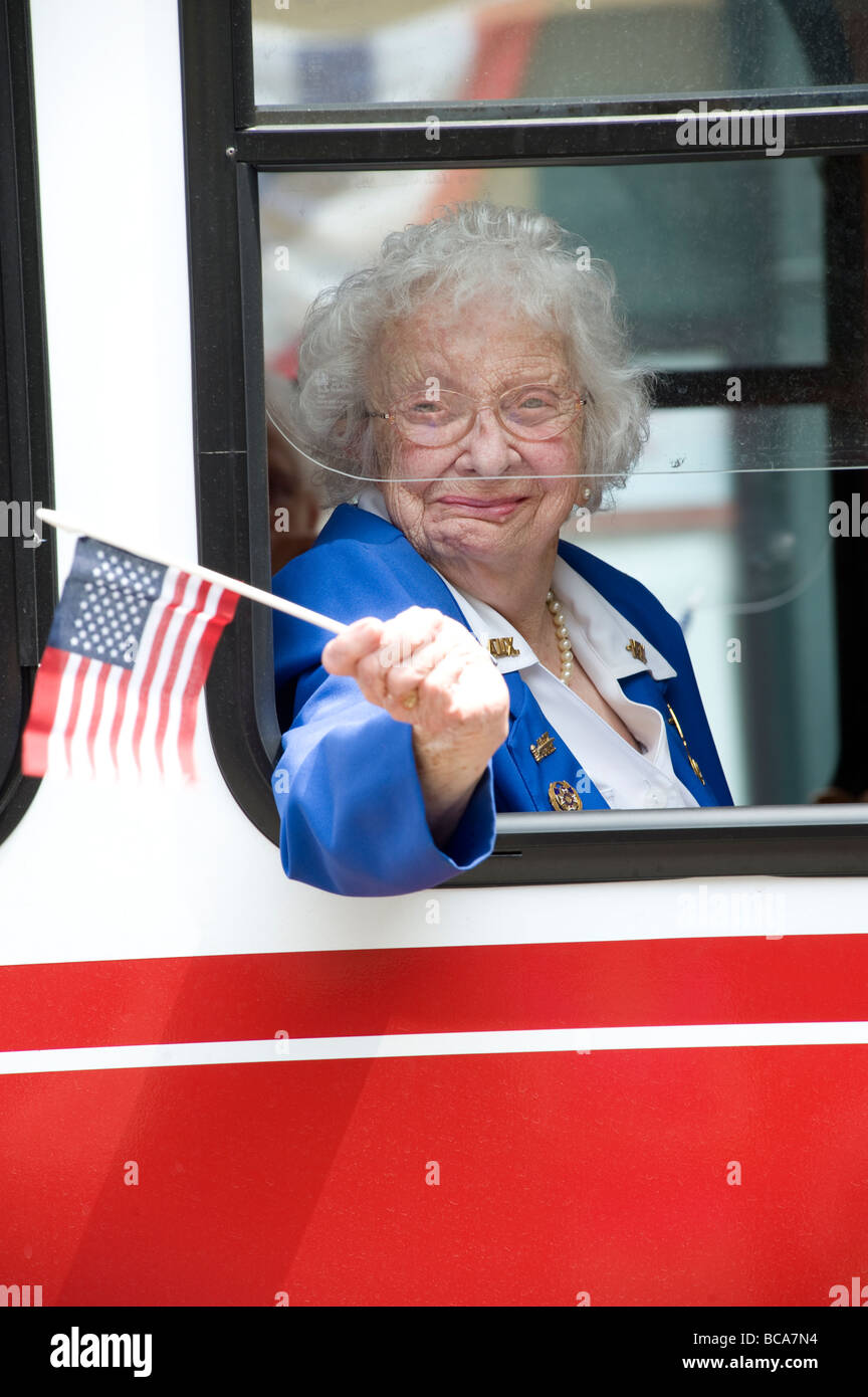 Femme âgée vagues drapeau comme elle participe au défilé commémoratif local Banque D'Images