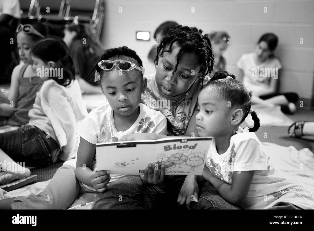 Trois petits enfants de l'école lire un livre dans une classe CT USA Banque D'Images