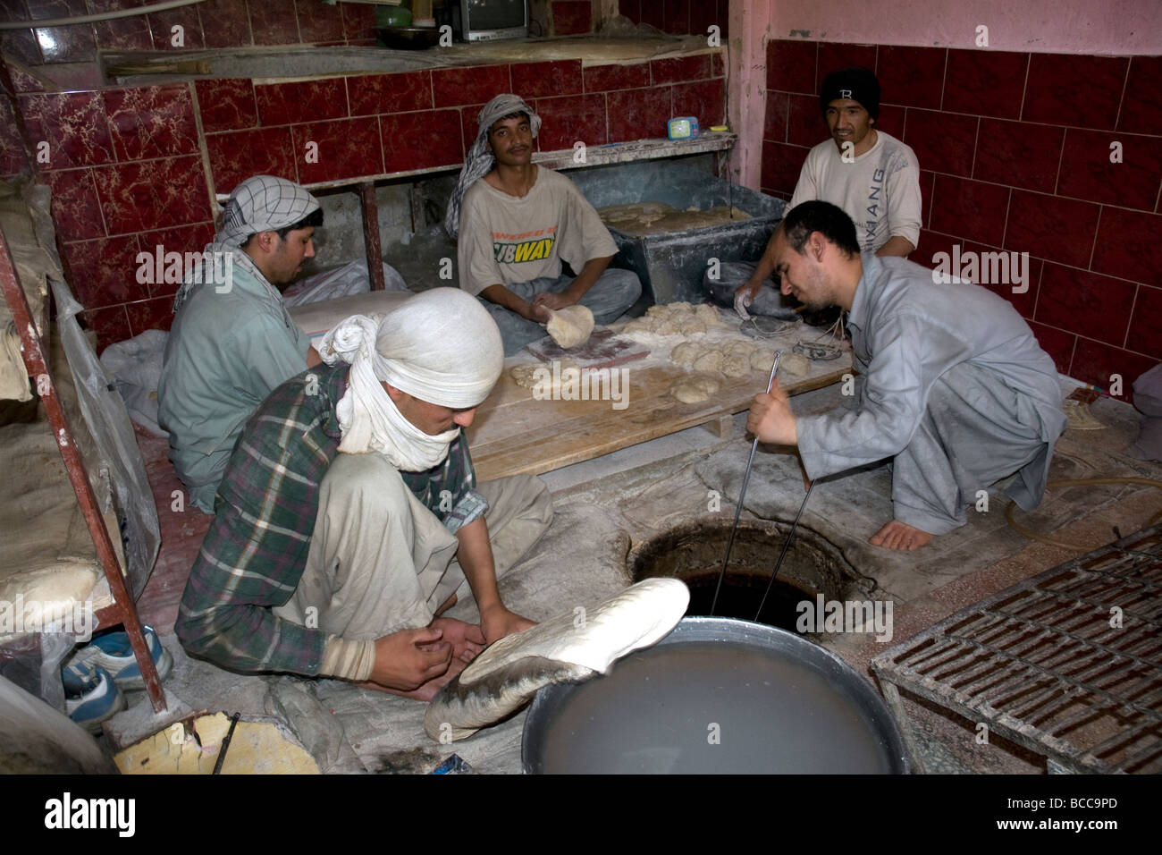 Dans une boulangerie dans la rue Poulet, Kaboul, assis les hommes font le pain national, Nan, le four dans un trou dans le plancher Banque D'Images