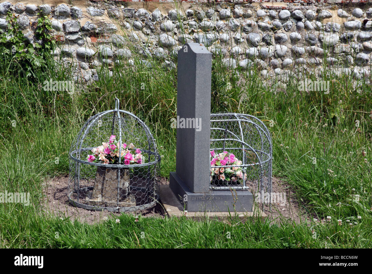 Des fleurs sur une tombe recouverte d'un panier métallique pour les arrêter d'être mangés par les lapins. Banque D'Images
