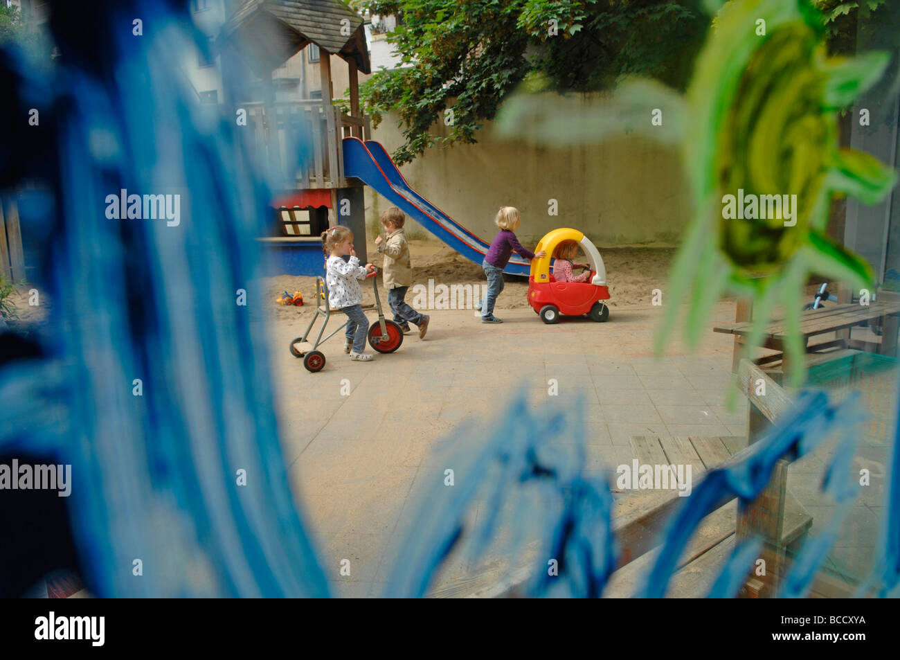 Les enfants et l'enseignant joue sur une aire de jeux dans un jardin d'un jour d'été. Banque D'Images
