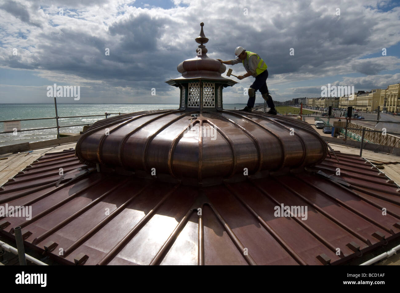 Un ouvrier martelant une nouvelle toiture en cuivre sur un kiosque victorien sur le front de mer de Brighton et Hove Banque D'Images