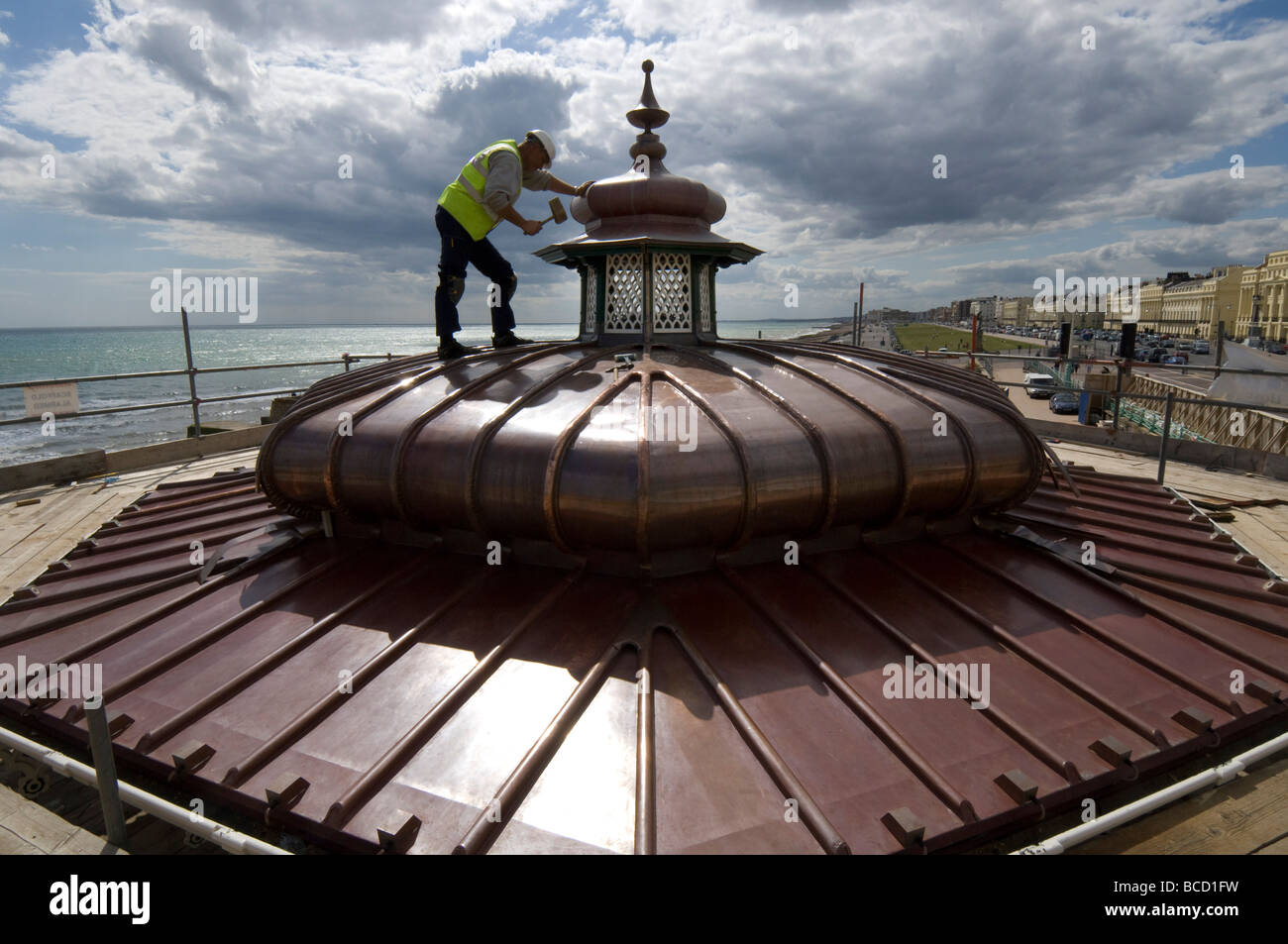 Un ouvrier martelant une nouvelle toiture en cuivre sur un kiosque victorien sur le front de mer de Brighton et Hove Banque D'Images