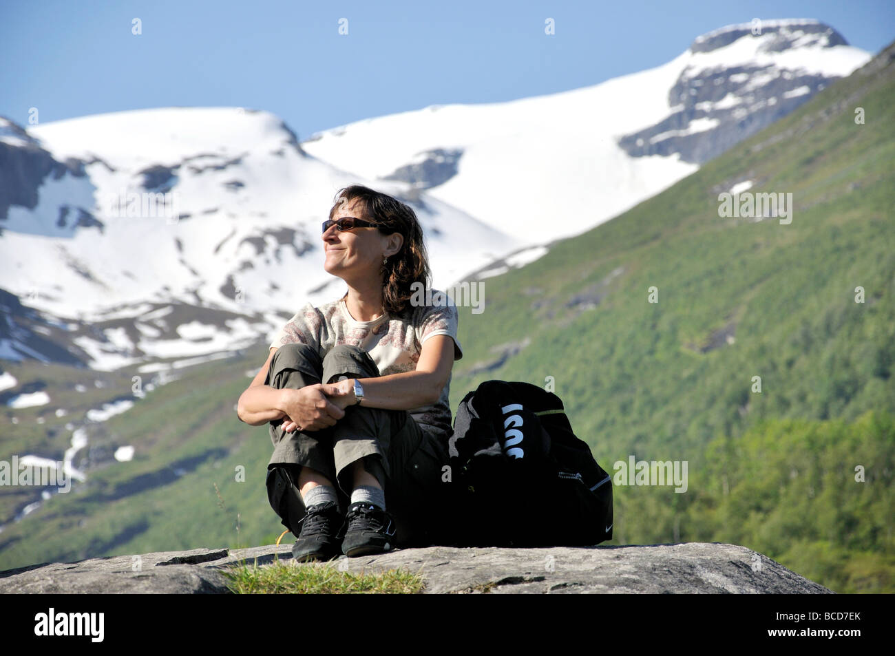 Woman relaxing on rock, Flydalsjuvet Viewport, Geiranger, More og Romsdal (Norvège) Banque D'Images