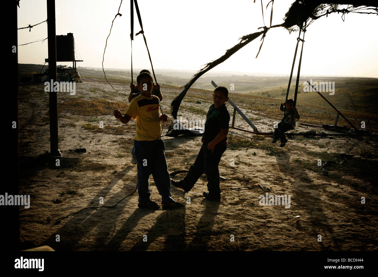 Les enfants jouent sur une balançoire improvisée dans le village bédouin non reconnu d'Al Araqeeb dans le désert du Néguev, Israël Banque D'Images