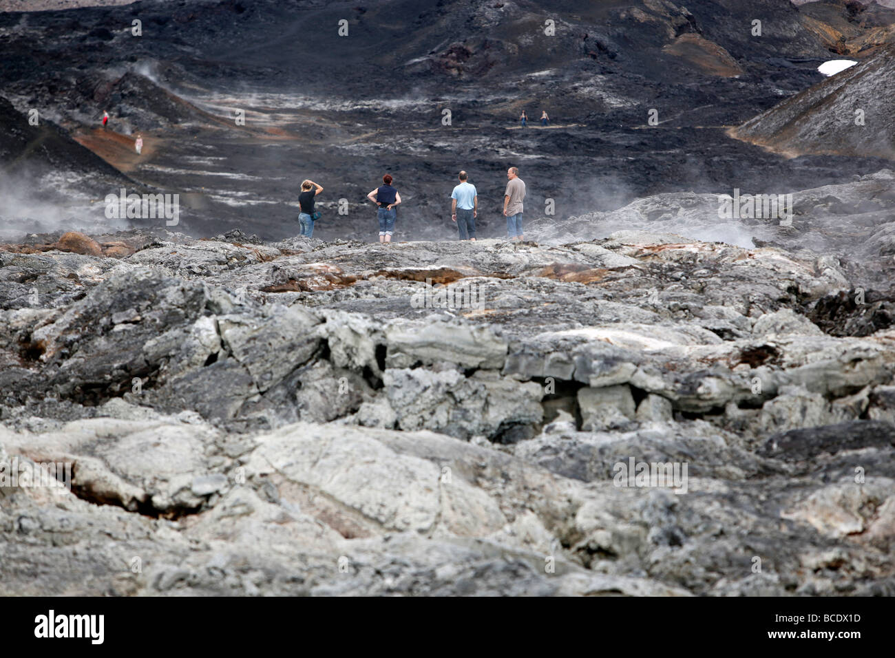 Quatre personnes regarder par dessus un champ de lave, Krafla, Islande Banque D'Images