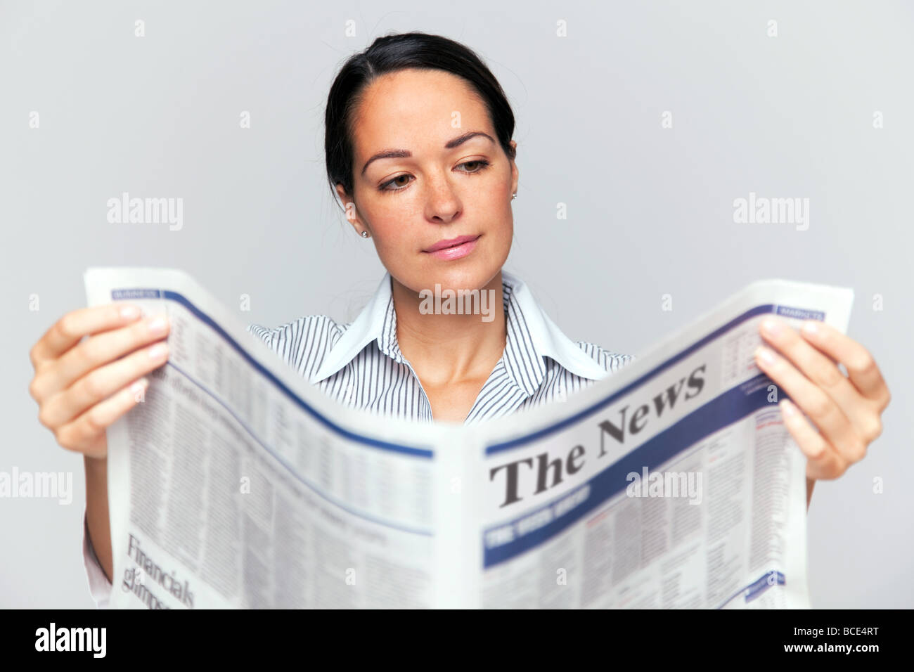 Businesswoman reading a newspaper focus est sur son visage et le journal est flou Banque D'Images