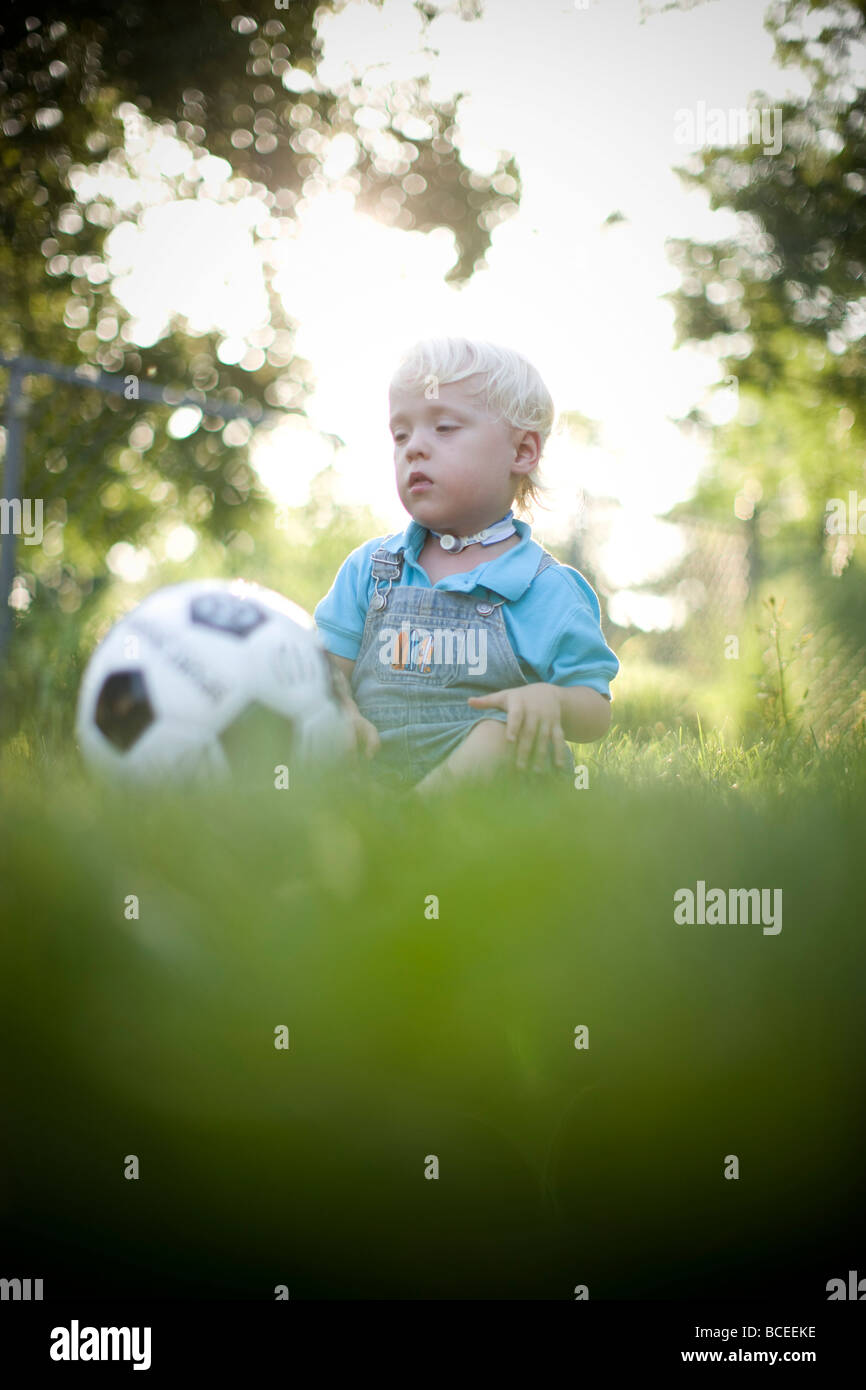 Jeune garçon jouant dehors avec un ballon de foot Banque D'Images