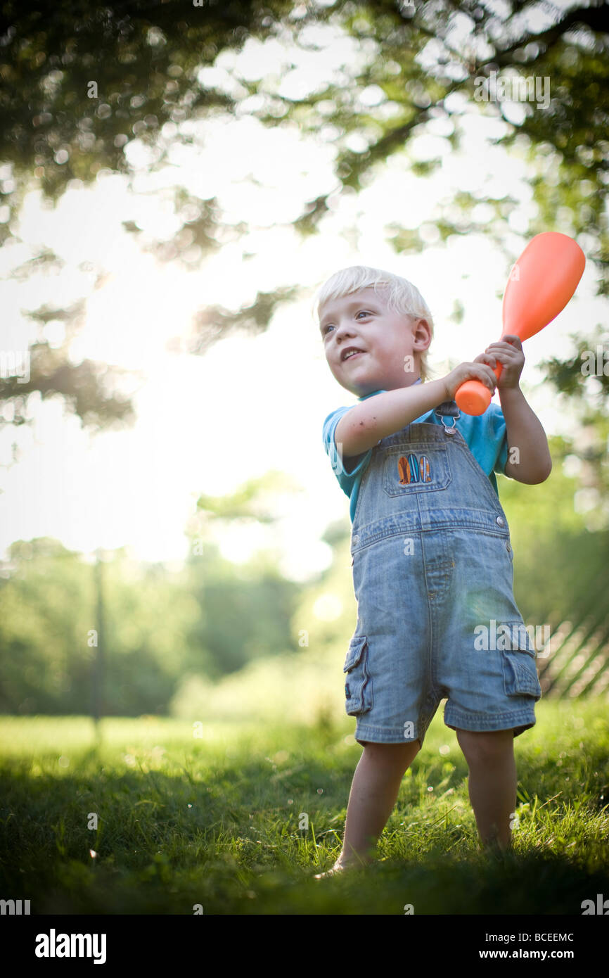 Enfant jouant dehors avec un bâton de baseball Banque D'Images