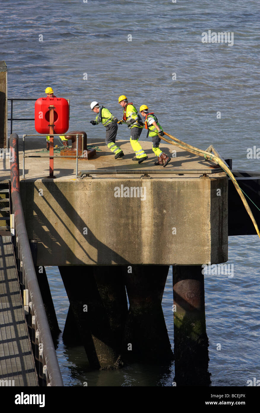 L'équipage du navire à terre tirer la corde dans quay tout en mouillage dans le port de Belfast, Irlande du Nord uk Banque D'Images