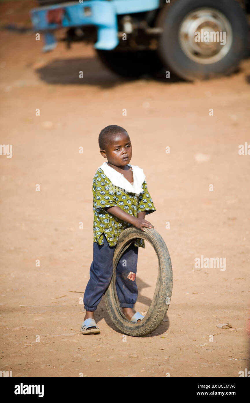 Garçon avec un pneumatique sur les rues du bidonville ougandais Banque D'Images