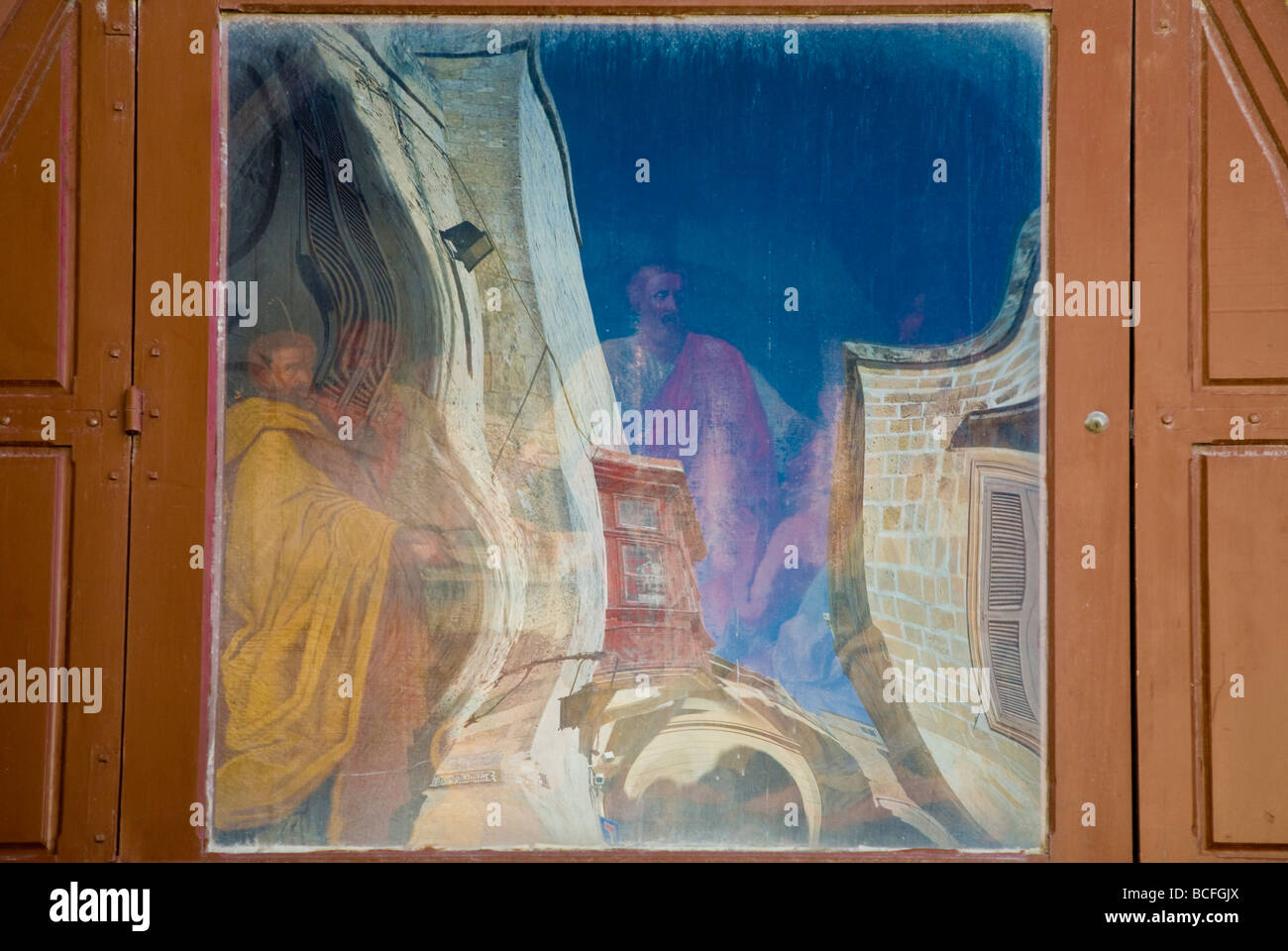 Reflet déformé de bâtiments étranges dans une fenêtre avec des icônes religieuses au-delà. La Valette, Malte, l'Union européenne. Banque D'Images