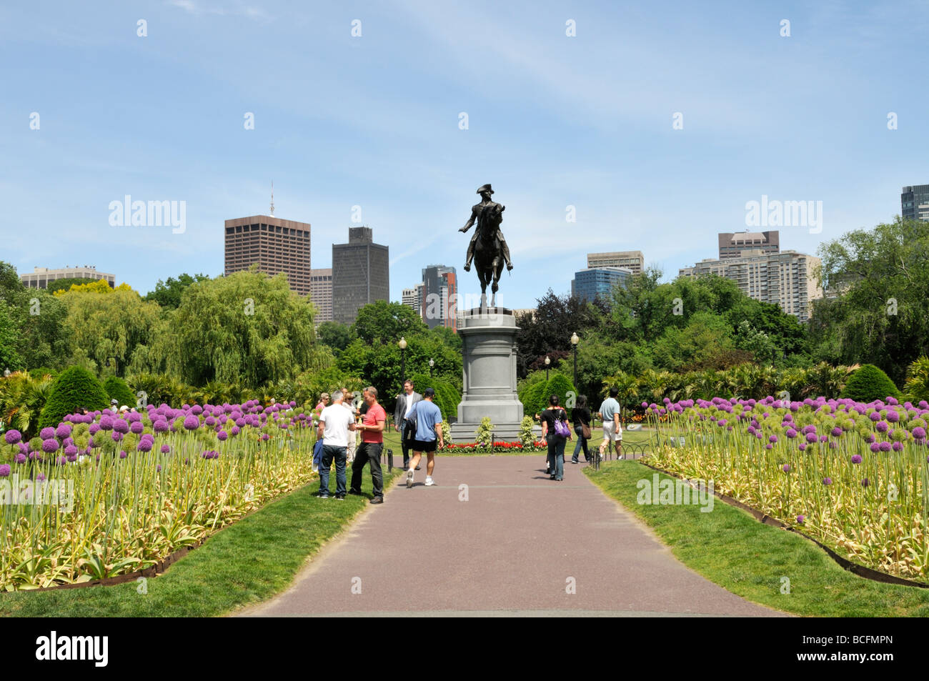 Dans les jardins publics à côté de Boston floraison commun Allium géant menant à statue de George Washington avec des toits de la ville Banque D'Images
