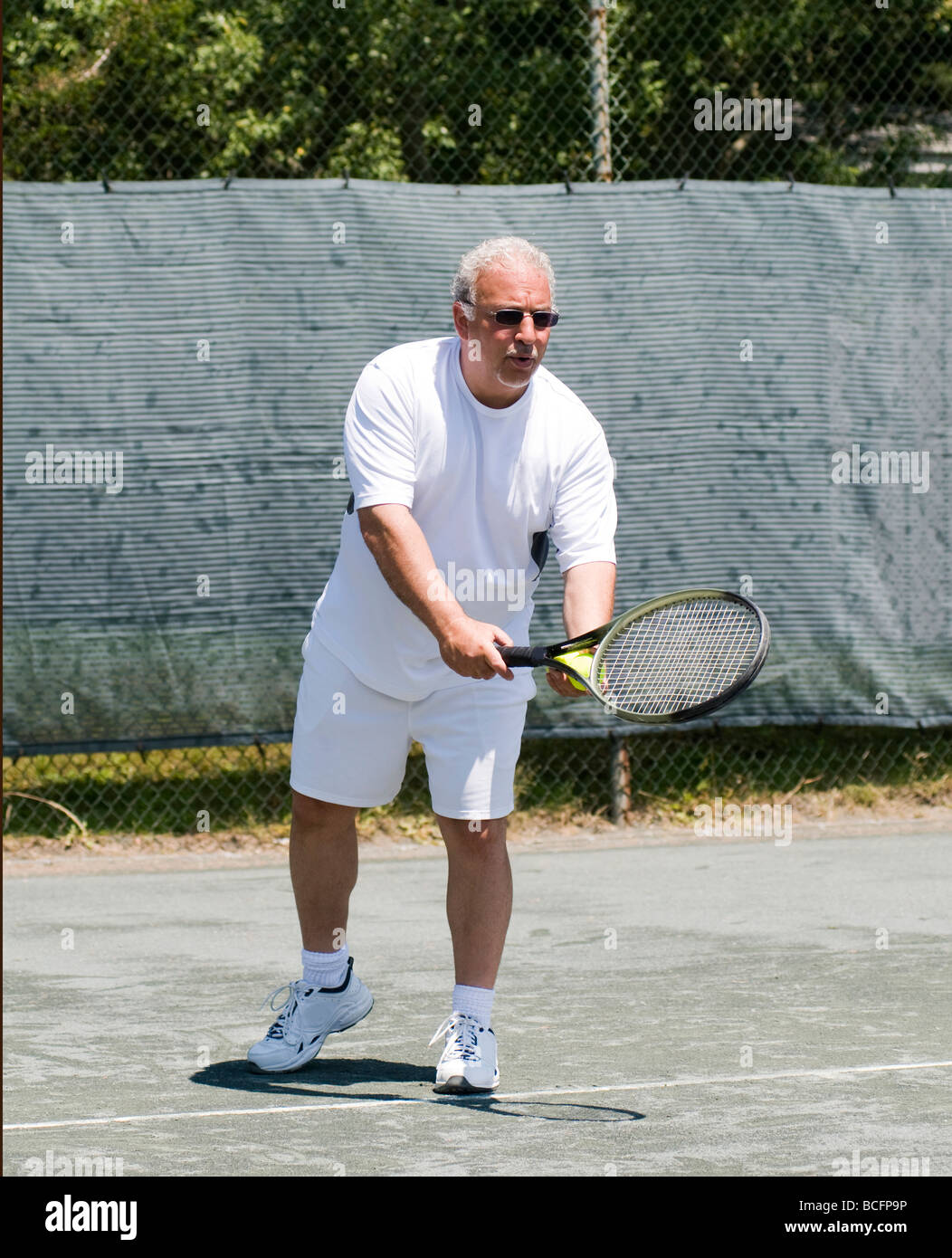 L'âge moyen beau joueur de tennis masculin frapper forehand stroke sur court de tennis au club Banque D'Images