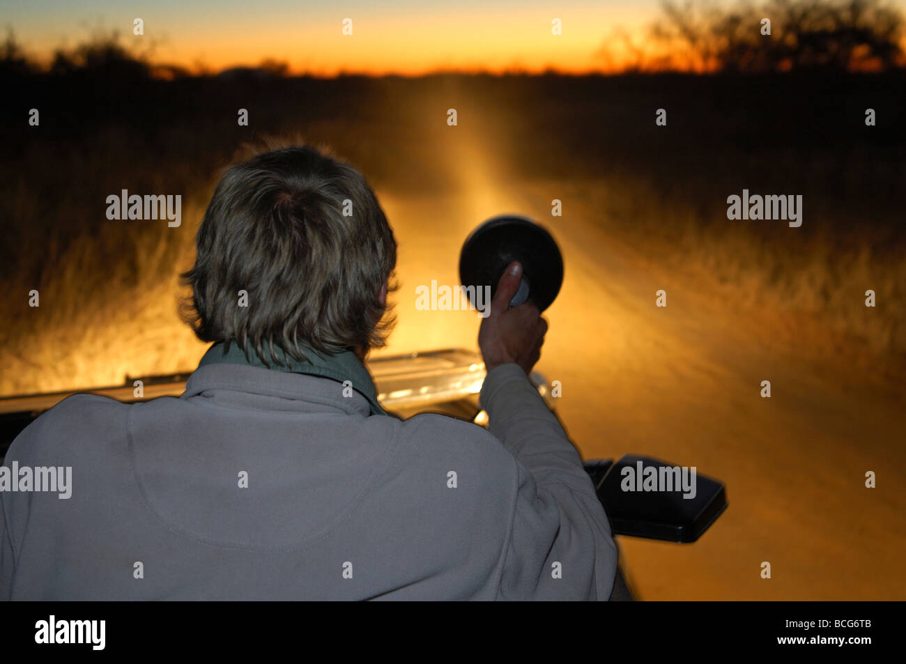 Ranger avec un spot light à la recherche d'animaux dans la savane africaine au cours d'une nuit de route, Madikwe Game Reserve, Afrique du Sud Banque D'Images