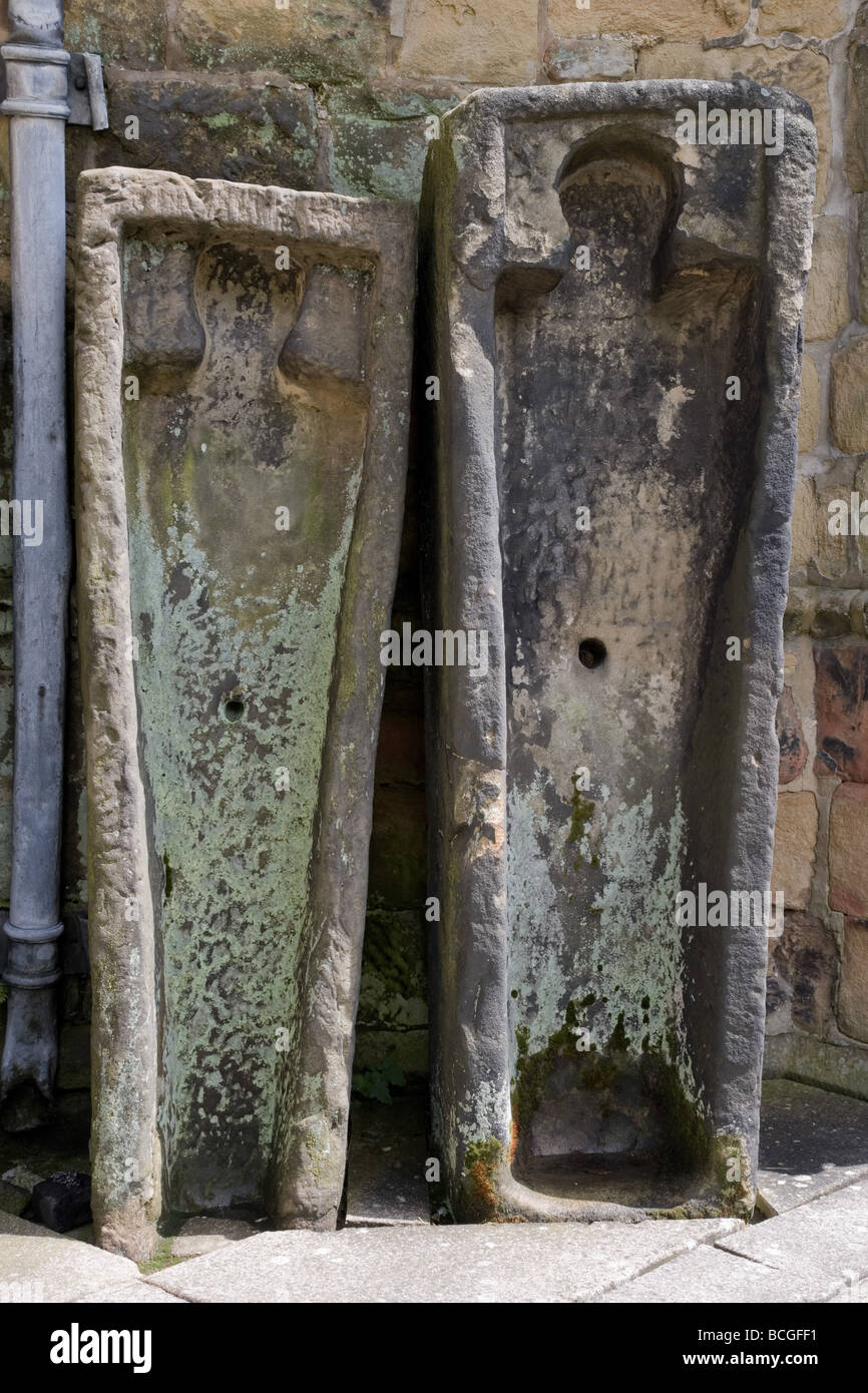 Des cercueils en pierre médiévale appuyé contre le mur du porche All Saints' Church, Bakewell Derbyshire Banque D'Images
