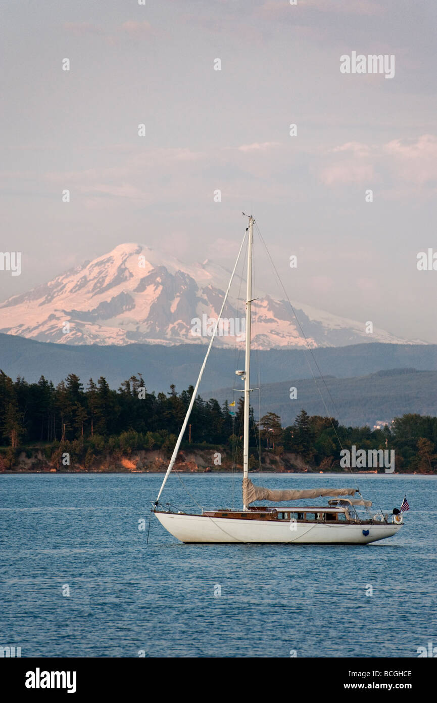 Un voilier au large de l'île de Lummi ancres, Washington. Mt enneigés. Baker et les Lummi Indian Reservation dominent l'arrière-plan. Banque D'Images