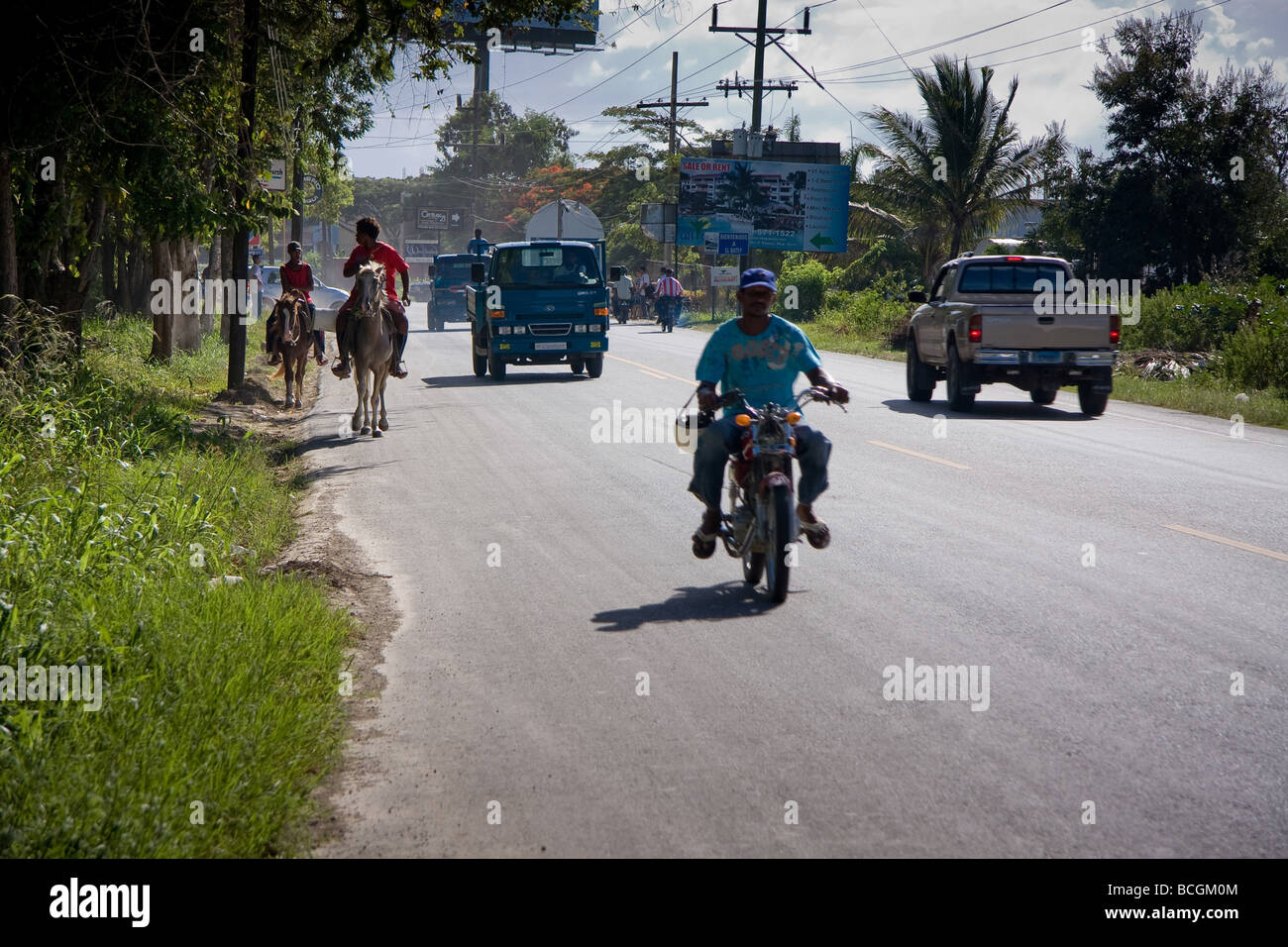 La vue depuis le côté d'une route achalandée à Sosua, République dominicaine montrant voitures, motos, cyclomoteurs, voitures et chevaux passant b Banque D'Images