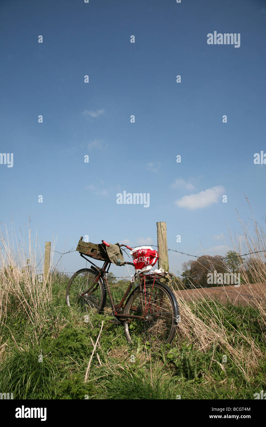 Un vieux vélo ou cycle pédale appuyée contre une clôture avec le ciel bleu en arrière-plan Banque D'Images