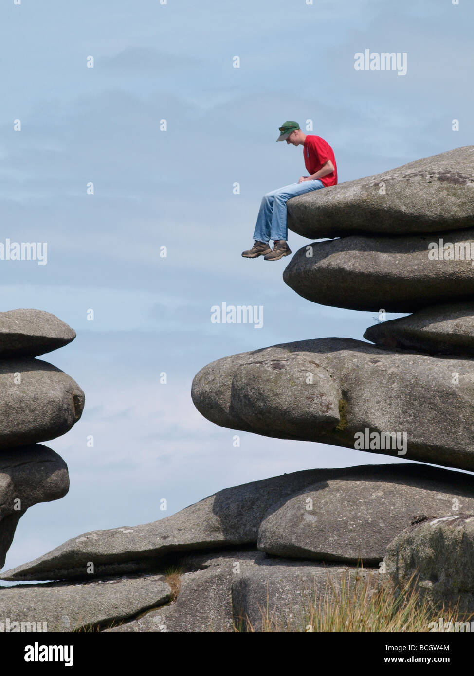 Adolescent assis sur des rochers sur le bord de la carrière de Cheesewring Cornwall Bodmin Moor Banque D'Images