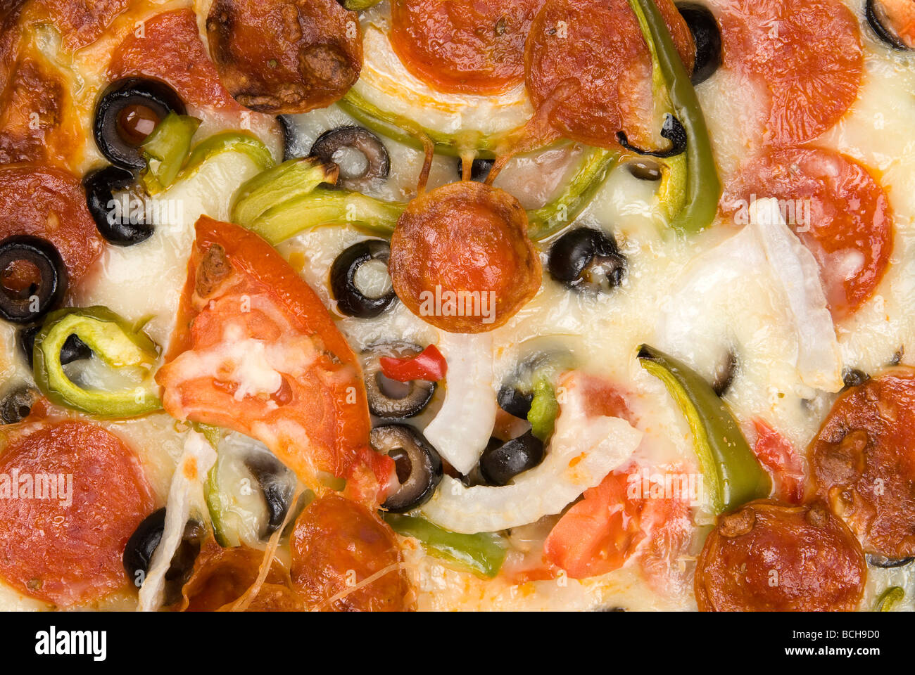 Gros plan d'une pizza avec l'usine, y compris les tomates mozzarella olives pepperoni et fromage cheddar, oignons et poivrons Banque D'Images
