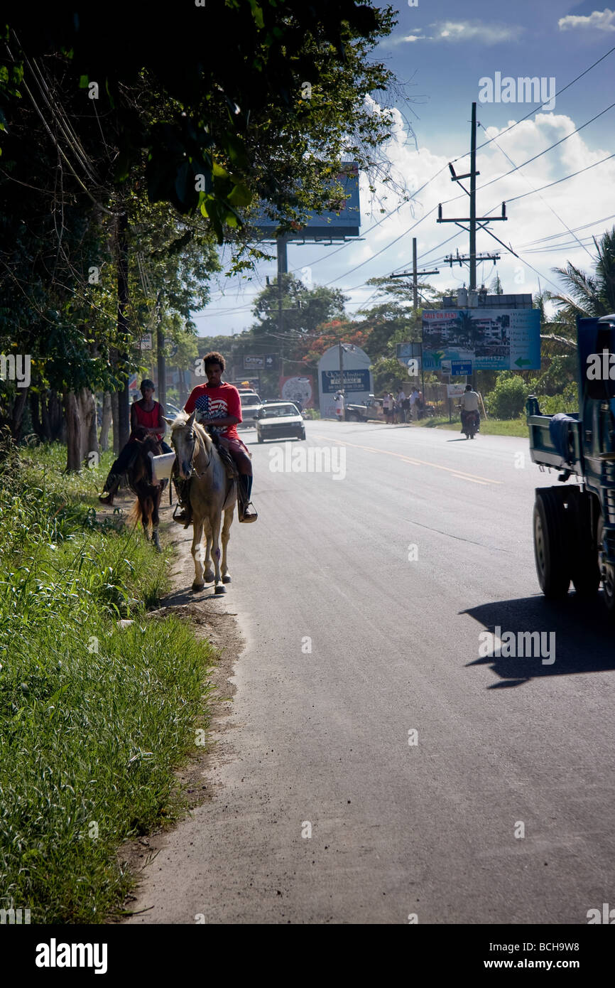 La vue depuis le côté d'une route achalandée à Sosua, République dominicaine montrant voitures, motos, cyclomoteurs, voitures et chevaux passant b Banque D'Images