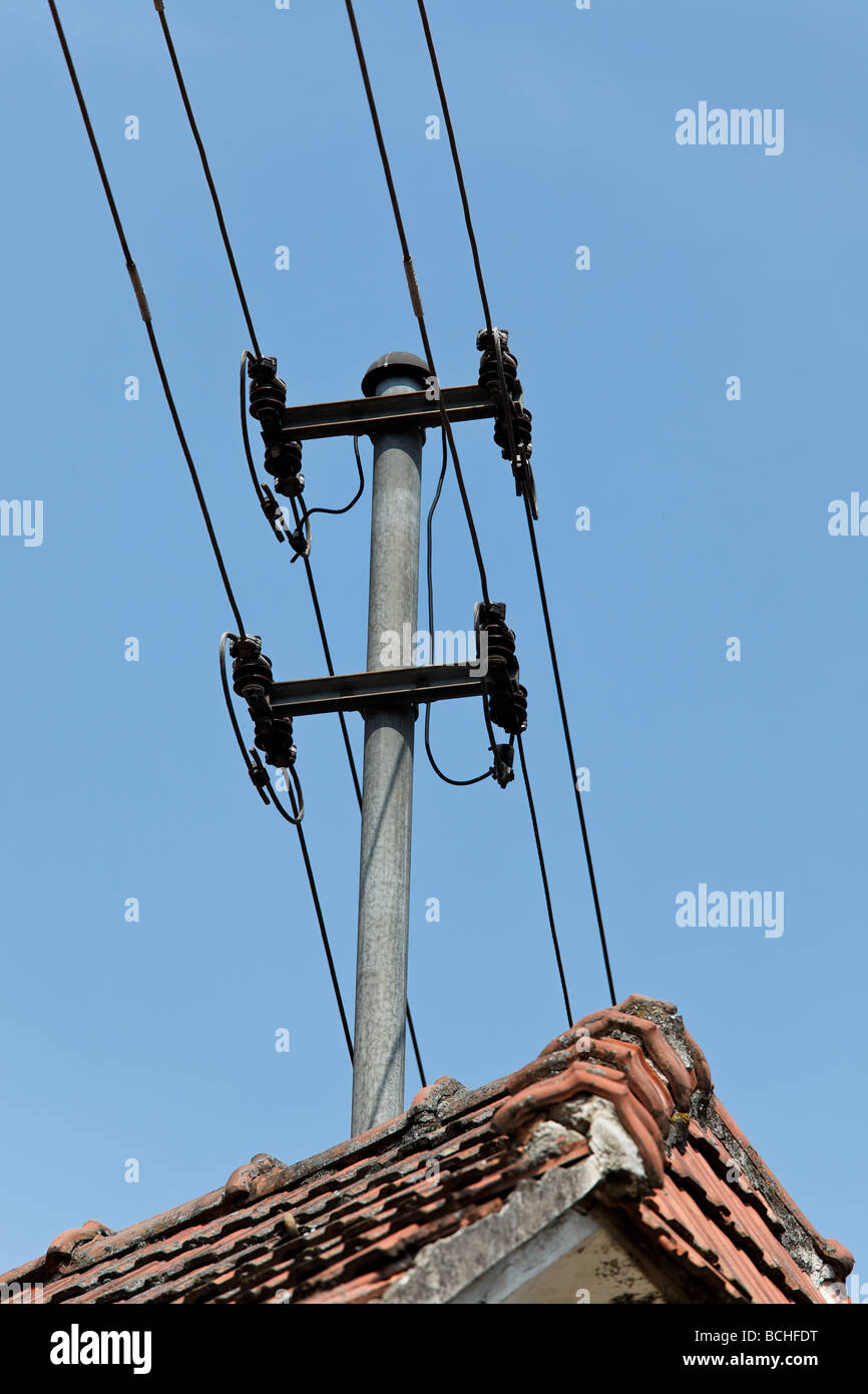 Porte-câbles d'électricité et de téléphone sur un toit de maison Banque D'Images