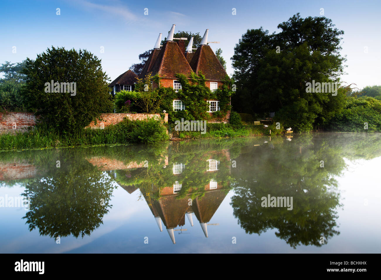 Oast house du Kent sur la rivière Medway tôt le matin avec des réflexions en miroir. Banque D'Images