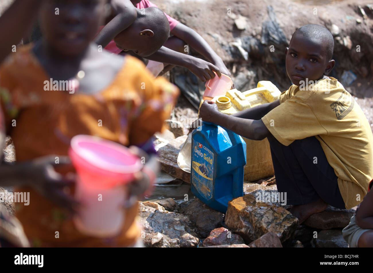 Les enfants vont chercher de l'eau contaminés de printemps. Kamwockya Kampala Ouganda Banque D'Images