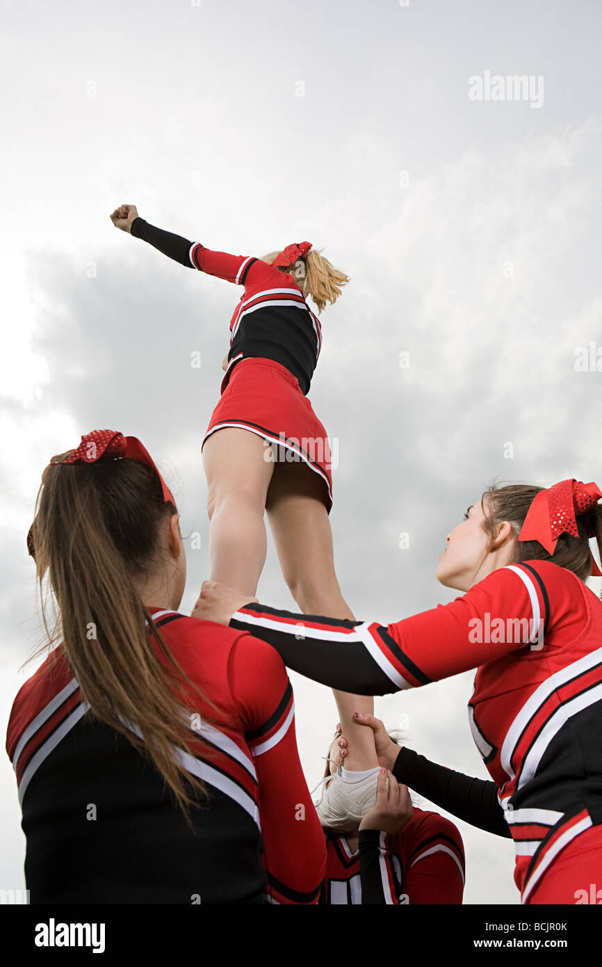Cheerleaders holding girl up Photo Stock - Alamy