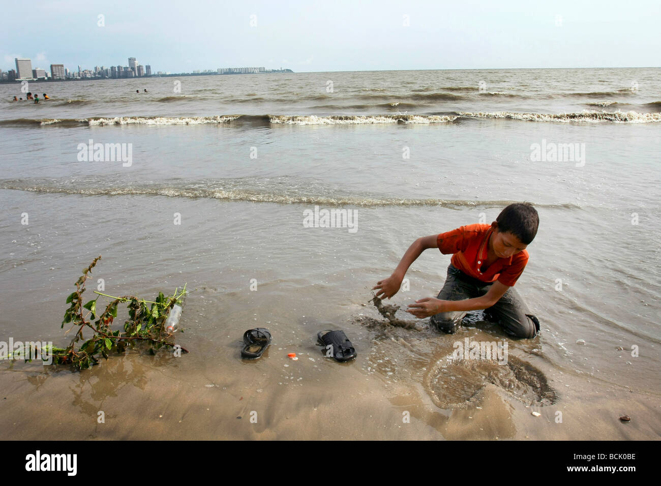 Un jeune garçon indien sculpte un coeur dans le sable sur la plage de Chowpatty à Mumbai (Bombay) en Inde Banque D'Images