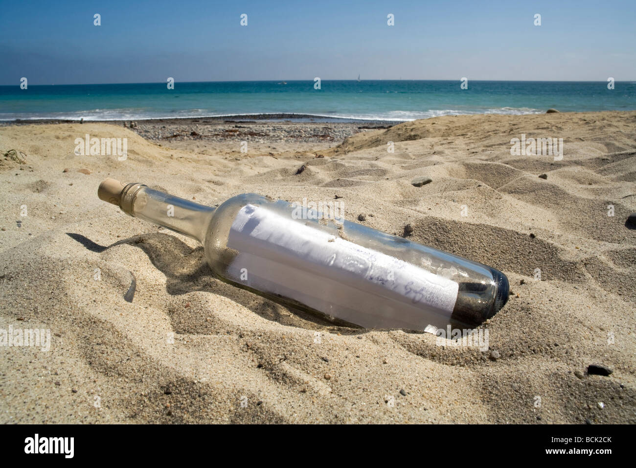 Une bouteille contenant un message se trouve sur une plage au coucher du soleil. Banque D'Images