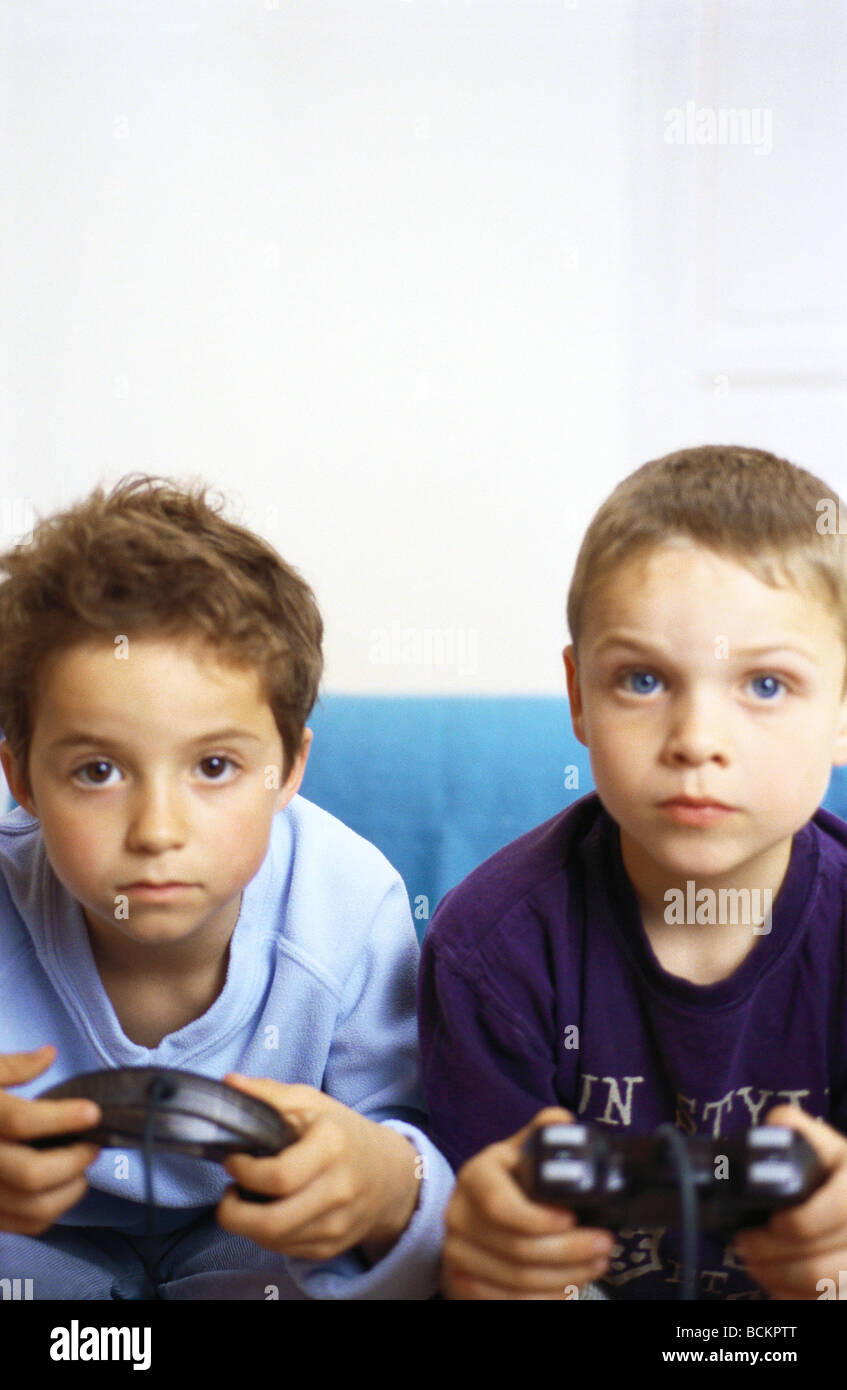 Deux garçons assis sur le canapé holding joysticks Banque D'Images