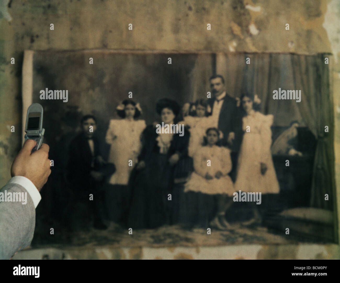 L'homme à l'aide d'un téléphone cellulaire pour la photographie noir et blanc d'une photo de famille sur le mur, cropped Banque D'Images