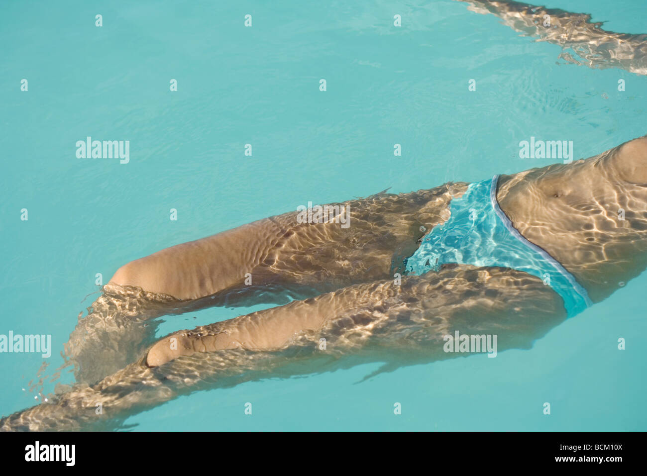 Femme flottant sur retour en piscine, cropped Banque D'Images