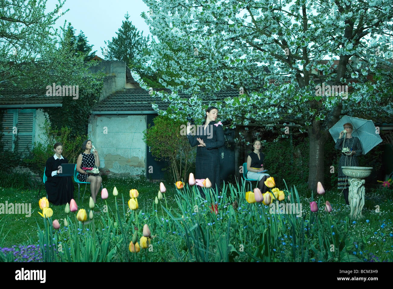 Les femmes au jardin dans diverses poses, utiliser des appareils électroniques Banque D'Images