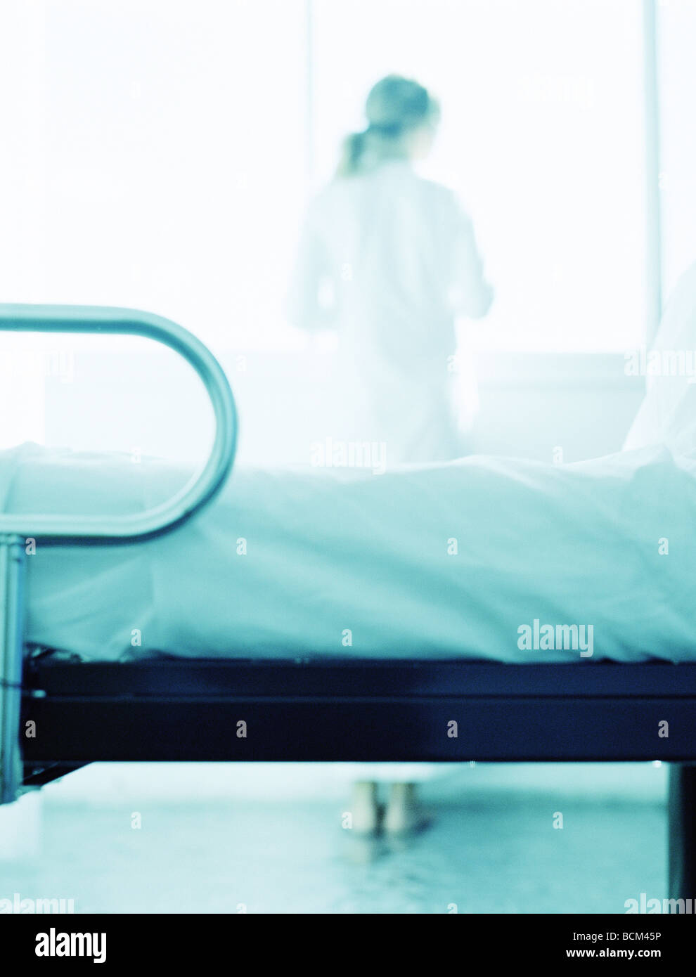 Patient standing in hospital room, looking out window, vue arrière Banque D'Images