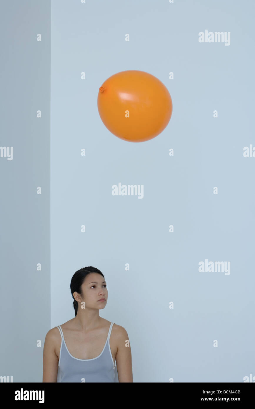 Ballon Orange flottant au-dessus tête de la femme, woman looking away Banque D'Images