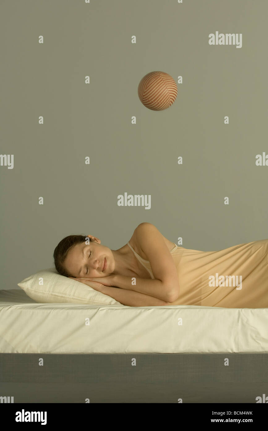 Woman sleeping in bed, sphère flottant dans l'air au-dessus de sa Banque D'Images