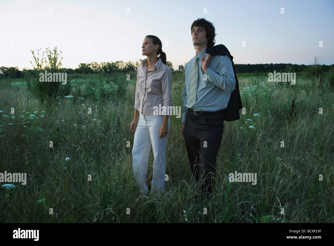 Bien-habillé couple standing in field at Dusk Banque D'Images