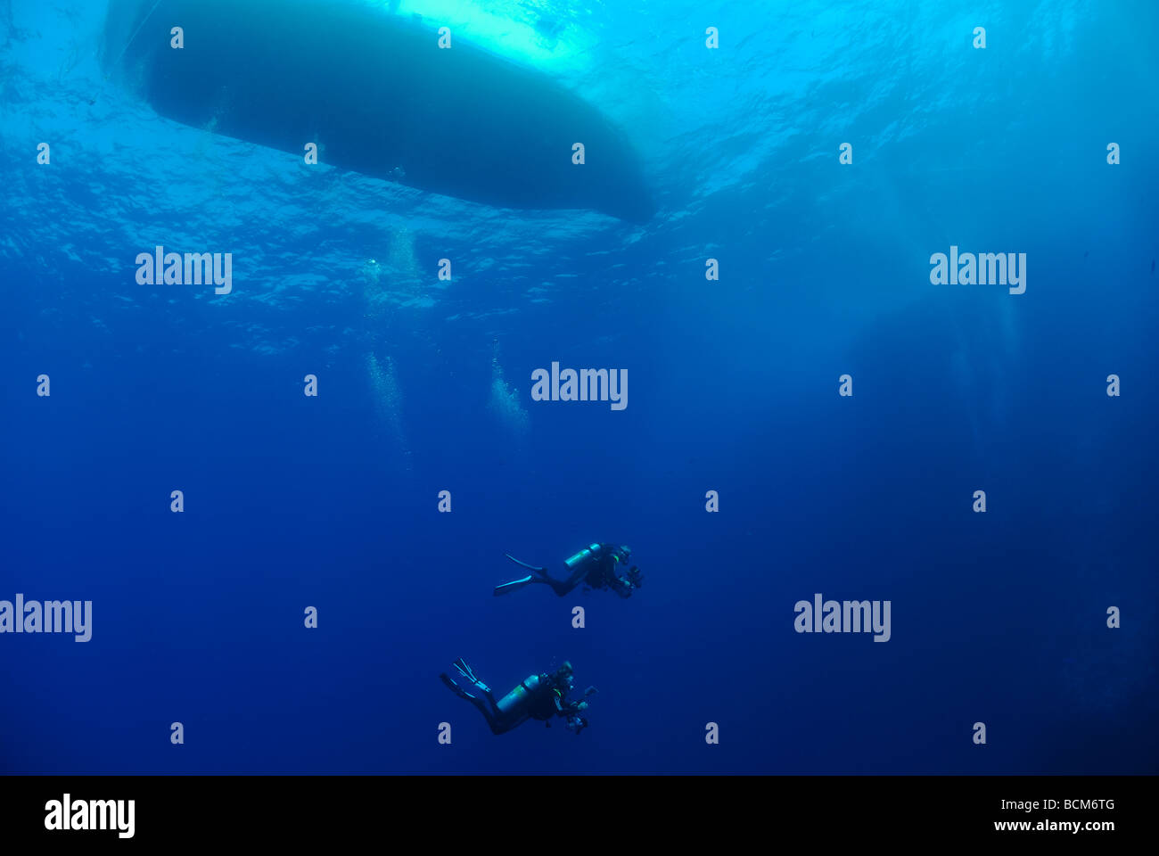 Deux plongeurs nage sous un bateau de plongée en Mer Rouge Banque D'Images
