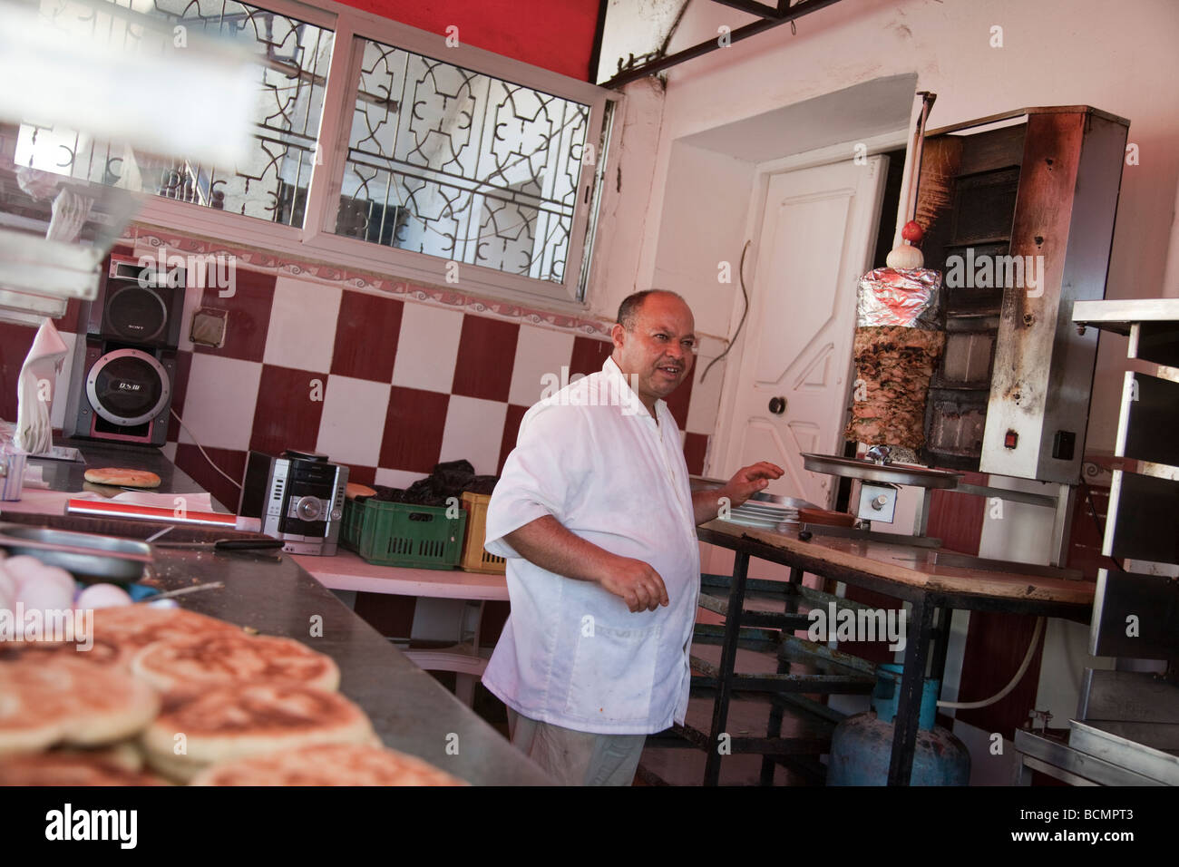 Un cuisinier dans un restaurant dans le Kef, Tunisie faire griller de la viande et des toasts de pain chappati. Banque D'Images