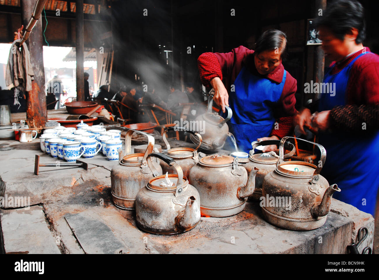 Deux femmes chinoises la préparation de l'eau chaude pour le thé dans une maison de thé local, Chengdu, province du Sichuan, Chine Banque D'Images