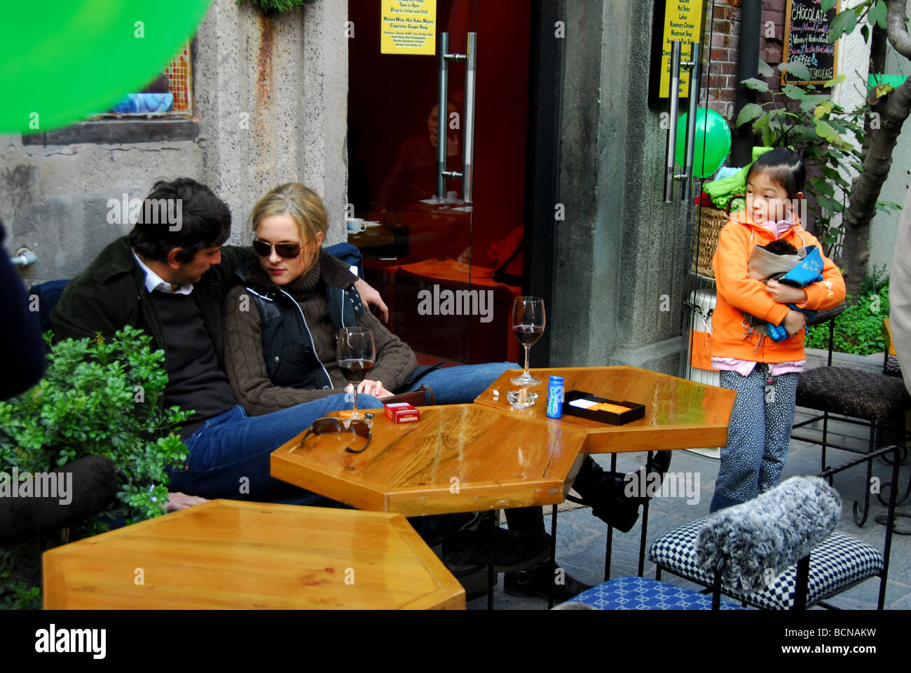 Couple étranger câlins à l'extérieur d'un restaurant branché sur Taikang Road artistique tandis qu'une jeune fille chinoise à la recherche sur, Banque D'Images